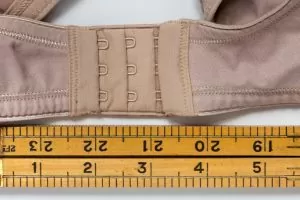 close up of a vintage inch scale with skin colored bra in the  backdrop