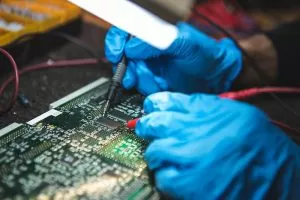 Tests electronic equipment, with protective gloves, in service centre. ( Focus on current clamp )